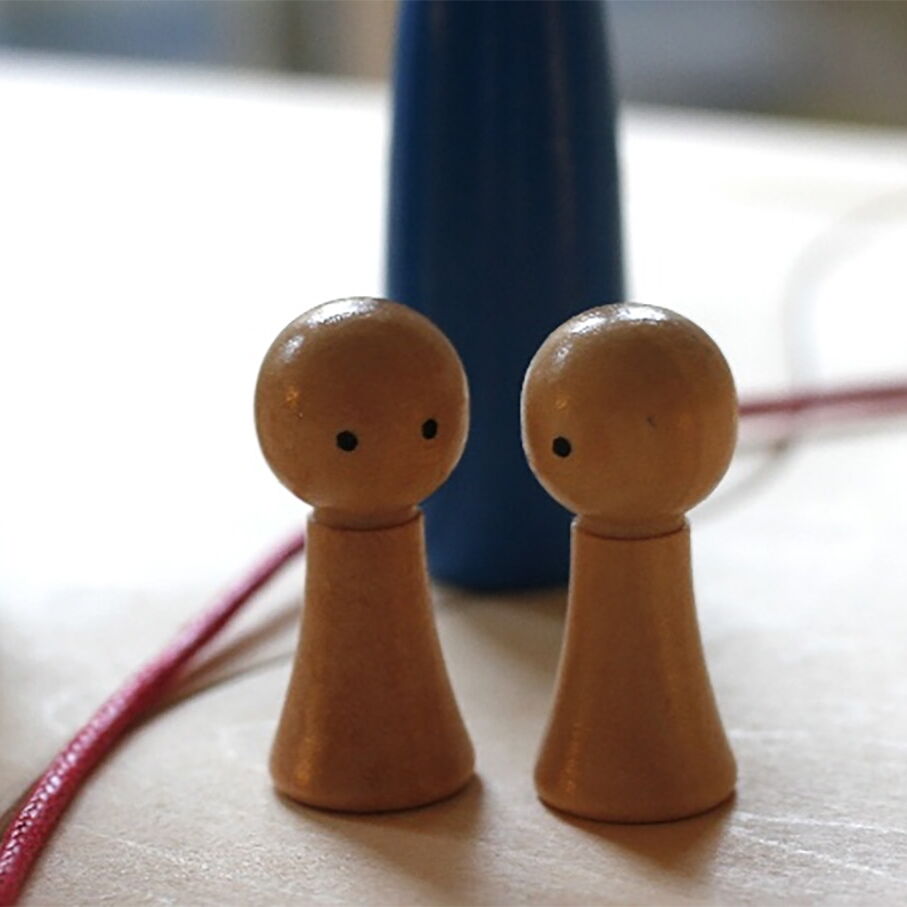 Zwei einander zugewandte Holzfiguren zeigen eine empathische Therapiesitzung